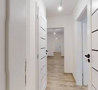 PREDAJ - 4-izb. byt na Sklenárovej ul., 67 m2, komplet. rekonštrukcia - Chodba 4-izbového bytu s podlahou s dreveným dekorom a bielymi dverami.