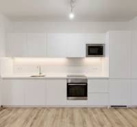 PREDAJ - 4-izb. byt na Sklenárovej ul., 67 m2, komplet. rekonštrukcia - Kuchyňa v 4-izbovom byte s bielou linkou a podlahou s dreveným dekorom.