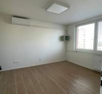 Prenajmem 1 izbový byt na Nábrežnej ulici v Nových Zámkoch - Izba s bielymi stenami a podlahou s dreveným dekorom v 1-izbovom byte.