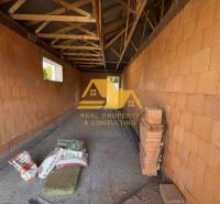 Predám novostavbu rodinného domu s garážou v Nových Zámkoch - Stavba rodinného domu na ulici v Nových Zámkoch s tehlovými stenami a trámovým stropom.