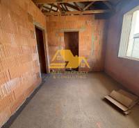 Predám novostavbu rodinného domu s garážou v Nových Zámkoch - Interiér rozostavaného rodinného domu s obnaženými tehlami a stavebnými materiálmi.