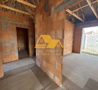 Predám novostavbu rodinného domu s garážou v Nových Zámkoch - Rozostavaný rodinný dom s pohľadom na steny bez omietky a dreveným krovom.