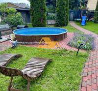 Predám peknú chatu na celoročné bývanie v Nových zámkoch - Záhrada chaty v Nových Zámkoch s bazénom, lehátkami a detským ihriskom.