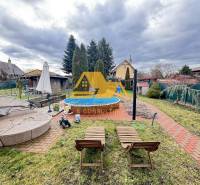 Predám peknú chatu na celoročné bývanie v Nových zámkoch - Záhrada pri chate s bazénom na ulici v Nových Zámkoch, obklopená udržiavanou zeleňou.