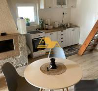 Predám peknú chatu na celoročné bývanie v Nových zámkoch - Interiér chaty so stolom, štyrmi stoličkami a kuchynským kútom s podlahou s dreveným dekorom.