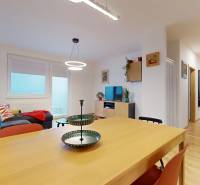 Na predaj moderný 3i byt v novostavbe Ovocné sady s parkovaním, BA - Obývačka v 3-izbovom byte s kuchynským stolom a podlahou s dreveným dekorom.