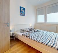 Na predaj moderný 3i byt v novostavbe Ovocné sady s parkovaním, BA - Spálňa v 3-izbovom byte s posteľou a oknom, podlaha s dreveným dekorom.