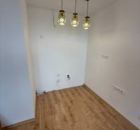 Na predaj 1,5-izbový byt v novostavbe GREENSIDE Trebišov - Interiér 1-izbového bytu s podlahou s dreveným dekorom a závesnými svietidlami.