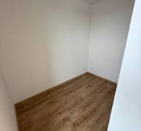 Na predaj 1,5-izbový byt v novostavbe GREENSIDE Trebišov - Prázdna miestnosť v 1-izbovom byte s podlahou s dreveným dekorom, biele steny.