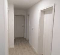 Rodinný dom v obci Bernolákovo, po kompletnej rekonštrukcii - Úzky chodba v rodinnom dome s bielymi stenami a podlahou s dreveným dekorom.