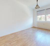 Predaj, trojizbový byt v Kremnici - Izba v 3-izbovom byte s bielymi stenami, podlahou s dreveným dekorom a oknom.
