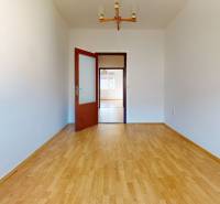 Predaj, trojizbový byt v Kremnici - Izba v 3-izbovom byte s podlahou s dreveným dekorom a bielymi stenami.