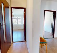 Predaj, trojizbový byt v Kremnici - Chodba v 3-izbovom byte s podlahou s dreveným dekorom a niekoľkými dverami.