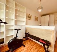 EXKLUZÍVNE! | Krásny 2-izbový byt | 52m² | Považanova - Izba s rotopedom v 2-izbovom byte, biele police, podlaha s dreveným dekorom.
