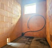 PRIESTRANNÁ 4-IZBOVÁ NOVOSTAVBA 167.38m²- BUNGALOV NA POZEMKU AŽ 702m² - Nedokončený interiér v rodinnom dome s pohľadovým murivom a otvorom pre okno.