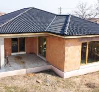 PRIESTRANNÁ 4-IZBOVÁ NOVOSTAVBA 167.38m²- BUNGALOV NA POZEMKU AŽ 702m² - Rodinný dom v Pavliciach s čiernou strechou a terasou v záhrade.