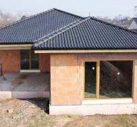 PRIESTRANNÁ 4-IZBOVÁ NOVOSTAVBA 167.38m²- BUNGALOV NA POZEMKU AŽ 702m² - Rodinný dom v Pavliciach vo výstavbe, tehlová fasáda, tmavá strecha, veľké okná.