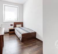 4-i., zariadený, lodžia, pivnica, internet, Röntgenova ul. - Izba s lôžkom, skrinkou a podlahou s dreveným dekorom v 4-izbovom byte.