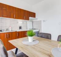 4-i., zariadený, lodžia, pivnica, internet, Röntgenova ul. - Kuchyňa 4-izbového bytu s dreveným dekorom a jedálenským stolom s rastlinou.