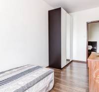 4-i., zariadený, lodžia, pivnica, internet, Röntgenova ul. - Izba v 4-izbovom byte s podlahou s dreveným dekorom, posteľou a vstavanou skriňou.