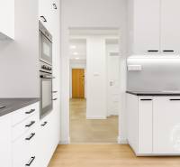 Nezariadený 3i byt po komp. rek. s lodžiou, Budyšínska - Kuchyňa v 3-izbovom byte s bielymi skrinkami a podlahou s dreveným dekorom.