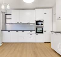 Nezariadený 3i byt po komp. rek. s lodžiou, Budyšínska - Kuchyňa v 3-izbovom byte s bielymi skrinkami a podlahou s dreveným dekorom.