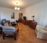 Ponúkame na prenájom priestranný 3-izbový byt v centre Martina  - Obývačka 3-izbového bytu s podlahou s dreveným dekorom, retro nábytkom a pohodlnými kreslami.