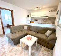 NIN-GRBLJANSKE VIKENDICE - dom s dvoma bytmi - Interiér rodinného domu s pohovkou, bielym stolom a kuchynským kútom.