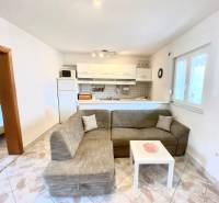 NIN-GRBLJANSKE VIKENDICE - dom s dvoma bytmi - Obývacia izba v rodinnom dome s pohovkou a kuchynským kútom, dlažba na podlahe.