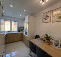 NA PREDAJ vkusne zrekonštruovaný  2 izbový byt, Komárno - Kuchyňa v 2-izbovom byte, svetlá dlažba, stôl s dekoráciami, obrázky na stene.