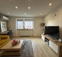 NA PREDAJ vkusne zrekonštruovaný  2 izbový byt, Komárno - Obývacia izba v 2-izbovom byte s podlahou s dreveným dekorom, gaučom a televízorom.