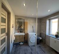 NA PREDAJ vkusne zrekonštruovaný  2 izbový byt, Komárno - Kúpeľňa v 2-izbovom byte s umývadlom, práčkou a dlažbou v dekore dreva.