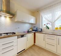 4-izbový dom 132m2 + pozemok 484m2 | Bernolákovo - Kuchyňa v rodinnom dome s bielymi skrinkami, chladničkou a veľkým oknom.