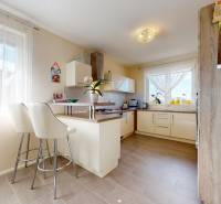 4-izbový dom 132m2 + pozemok 484m2 | Bernolákovo - Kuchyňa v rodinnom dome s barovými stoličkami a podlahou s dreveným dekorom.