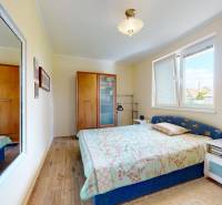 4-izbový dom 132m2 + pozemok 484m2 | Bernolákovo - Spálňa v rodinnom dome s podlahou s dreveným dekorom, zrkadlom a posteľou.