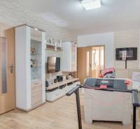 3-izbový byt s loggiou na ul. S.H. Vajanského, Nové Zámky – 74,69m2 - Obývacia izba v 3-izbovom byte s podlahou s dreveným dekorom a rohovou sedačkou.