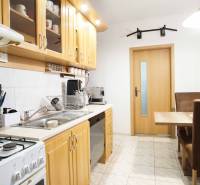 3-izbový byt s loggiou na ul. S.H. Vajanského, Nové Zámky – 74,69m2 - Kuchyňa v 3-izbovom byte s drevenými skrinkami a jedálenským stolom.