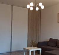 Prenájom 2-izbový byt na začiatku Petržalky - Obývacia izba s pohovkou, stolíkom a podlahou s dreveným dekorom v 2-izbovom byte.