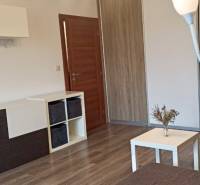 Prenájom 2-izbový byt na začiatku Petržalky - Obývacia izba v 2-izbovom byte s podlahou s dreveným dekorom a moderným nábytkom.