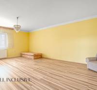 NA PREDAJ 3-IZBOVÝ RODINNÝ DOM, PUSTÉ ÚĽANY - Žltá izba s kreslom a pohovkou, podlaha s dreveným dekorom.