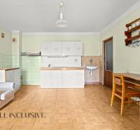 NA PREDAJ 3-IZBOVÝ RODINNÝ DOM, PUSTÉ ÚĽANY - Interiér rodinného domu s kuchynskou linkou, kreslom a stolom, podlaha s dreveným dekorom.