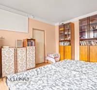 NA PREDAJ 5-IZBOVÝ RODINNÝ DOM NA 15Á POZEMKU,ŠALGOČKA - Interiér rodinného domu s drevodekorovou podlahou, knihovňou a elegantným posteľným pokrytím.