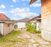 NA PREDAJ 5-IZBOVÝ RODINNÝ DOM NA 15Á POZEMKU,ŠALGOČKA - Rodinný dom v Šalgočke so strechami a neopravenou tehlovou stenou, vedľa je rebrík.