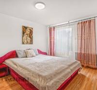 NA PREDAJ 5-IZBOVÝ RODINNÝ DOM NA 15Á POZEMKU,ŠALGOČKA - Spálňa s červenou posteľou, podlahou s dreveným dekorom a zaujímavým obrazom v rodinnom dome.