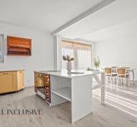 REZERVOVANÉ 5-IZBOVÝ RODINNÝ DOM VO VEĽKEJ PAKE - Kuchyňa v rodinnom dome s podlahou s dreveným dekorom, svetlým nábytkom a veľkým oknom.