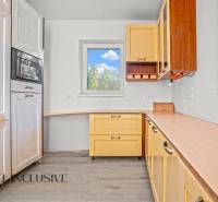 REZERVOVANÉ 5-IZBOVÝ RODINNÝ DOM VO VEĽKEJ PAKE - Kuchyňa v rodinnom dome s podlahou s dreveným dekorom a žltými skrinkami.