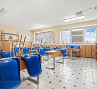 NA PREDAJ ŠKOLSKÁ BUDOVA NA VEĽKOM POZEMKU, MOSTOVÁ - Trieda v budove so stoličkami na stoloch, dlaždicová podlaha, prirodzené svetlo.