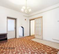 Na predaj 4-izbový rodinný dom, Gabčíkovo - Izba v rodinnom dome s lustrom, štruktúrovanou podlahou a dreveným nábytkom.