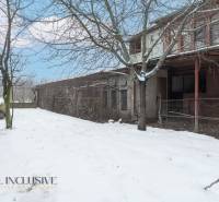 Na predaj 4-izbový rodinný dom, Gabčíkovo - Snehom pokrytý dvor rodinného domu v Gabčíkove s holými stromami a starou budovou.