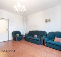 Na predaj 4-izbový rodinný dom, Gabčíkovo - Obývacia izba s tmavozelenou sedačkou, podlahou s dreveným dekorom a svetlom na strope.